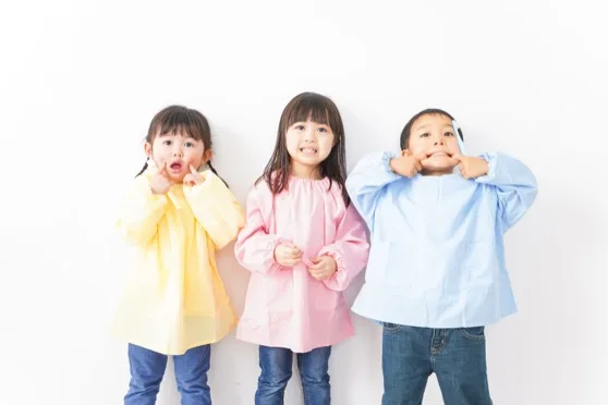 レインコートを着た3人の子どもが笑っている様子