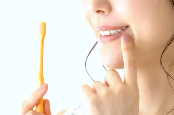 歯ブラシを持った女性が白い歯を指さしている様子