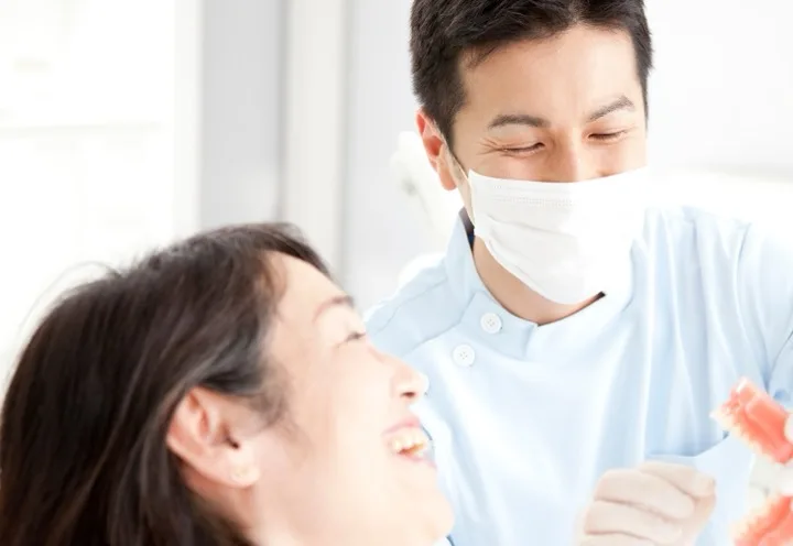 歯科医師が歯の模型を使って患者に説明している様子