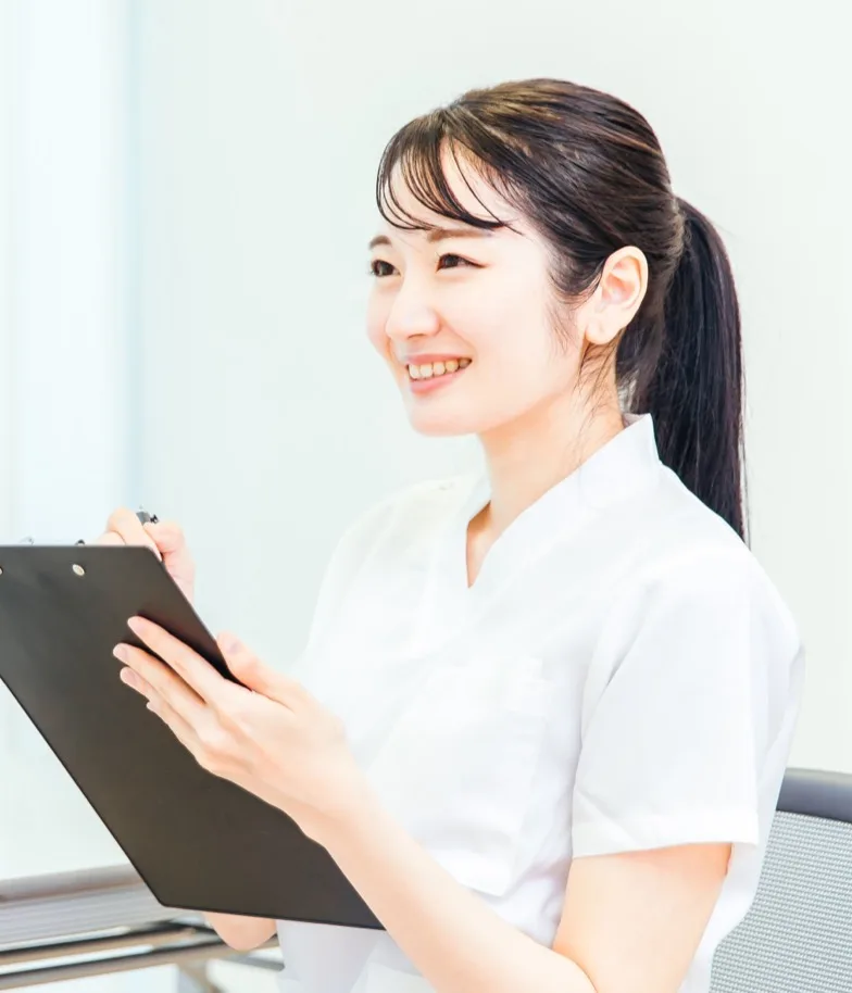 バインダーを手に笑顔で立つ受付・アシスタントの田中理恵
