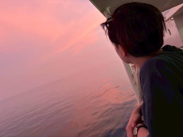 夕焼けに染まる海を眺めている写真