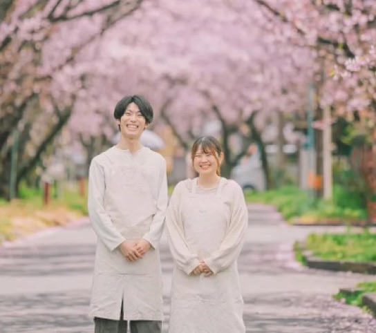 加工後。晴れた日のように明るく桜が色づいた並木に仕上げた同じ2人の写真
