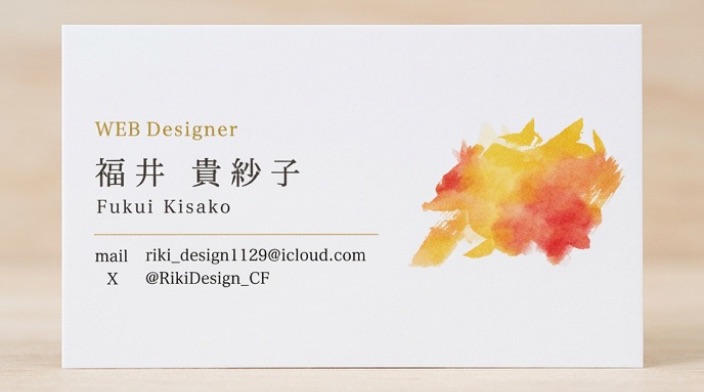 WEB Designer 福井貴紗子の名刺。白地に水彩のオレンジのイラストと連絡先が入っている