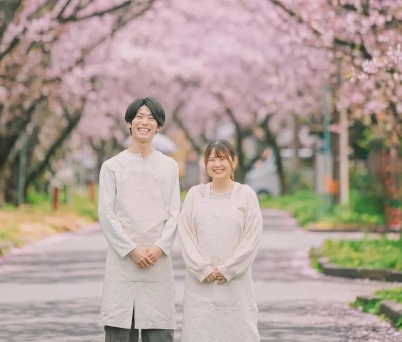 桜を咲かせて温かな雰囲気に加工した店主夫婦の写真