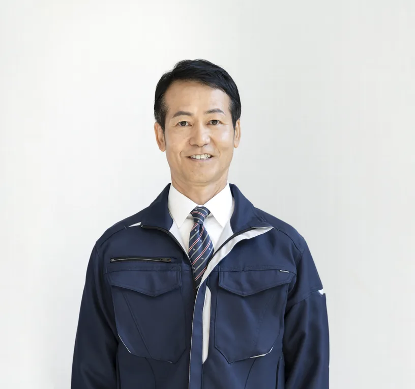 紺色の作業着で笑顔を見せる代表取締役